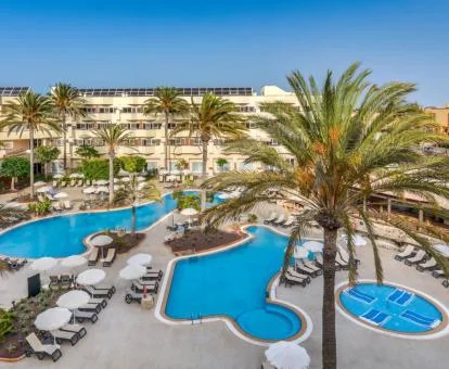 Fabuloso hotel con varias piscinas al aire libre, solarium con tumbonas y jardines con palmeras.