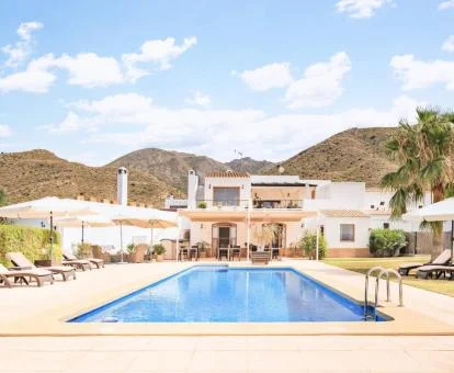 Edificio de este hotel rural con piscina exterior rodeado de montañas.
