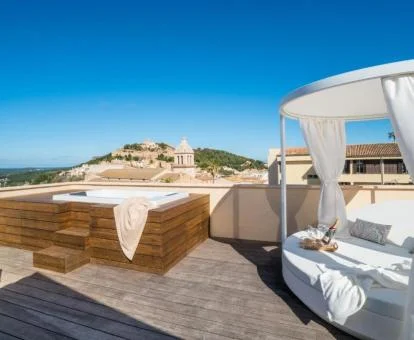 Jacuzzi exterior y cama redonda en una terraza privada con bonitas vistas.