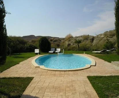 Amplios jardines con piscina exterior de este hotel boutique enclavado en una cueva.