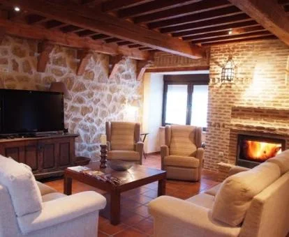 Acogedora zona de estar compartida con chimenea y televisión de estilo rústico de este alojamiento rural.