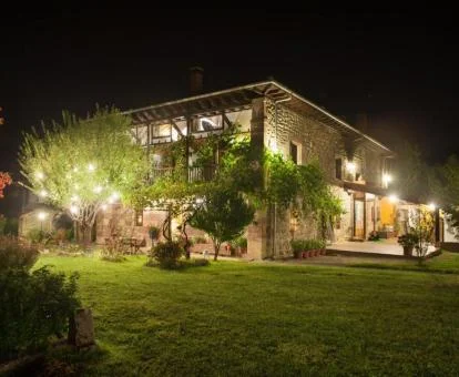 Hermoso hotel rural con amplios jardines e iluminación nocturna.