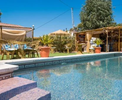 Piscina exterior con jardines y mobiliario al aire libre de este hotel.