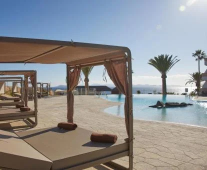 Piscina exterior con vistas al mar y solarium con camas balinesas.