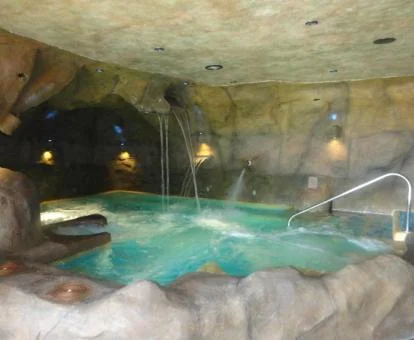 Piscina cubierta de tipo cueva con hidroterapia del spa del hotel.