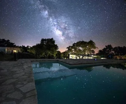 Fabulosa piscina con vistas a la naturaleza de este hotel con encanto en una bella noche estrellada.