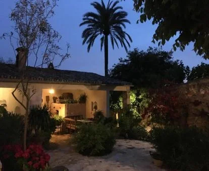 Fachada de este hotel rural rodeado de vegetación con iluminación nocturna.