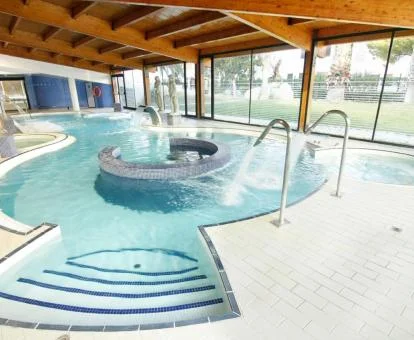 Piscina cubierta con hidroterapia y vistas al exterior del centro de bienestar del hotel.