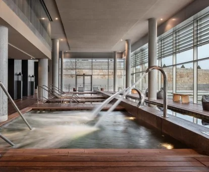 Piscina cubierta con hidroterapia y vistas al exterior del centro de bienestar del hotel.