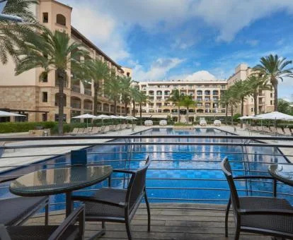 Precioso hotel con una gran piscina al aire libre rodeada de palmeras.