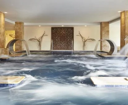 Gran piscina con elementos de hidroterapia en funcionamiento del spa del hotel.