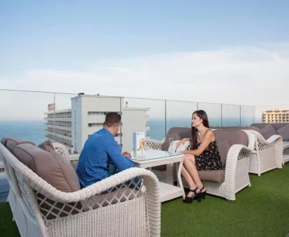 Pareja disfrutando de la terraza con mobiliario exterior y vistas al mar del hotel.