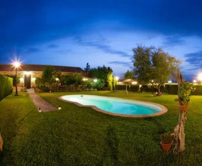Edificio de este alojamiento rural con piscina exterior rodeada de jardines.