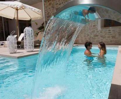 Pareja disfrutando de la piscina con chorros de hidroterapia del spa.