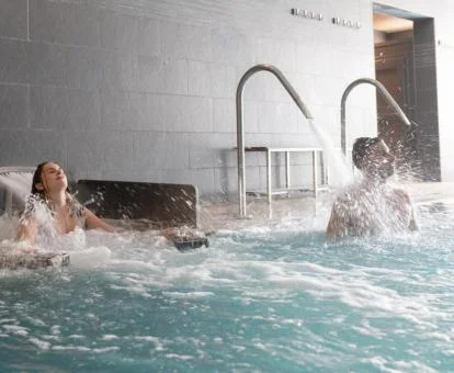 Pareja disfrutando de la piscina de hidroterapia del spa.