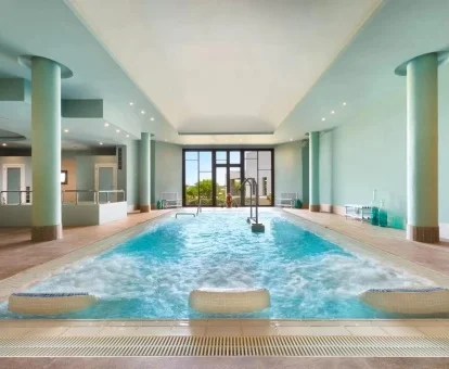 Piscina cubierta con hidroterapia y vistas al exterior del centro de bienestar del hotel.