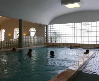 Varias personas disfrutando de la piscina cubierta del centro de spa.