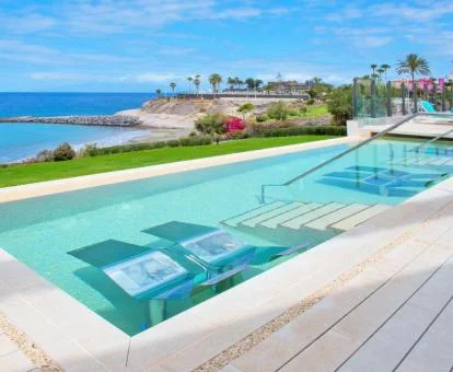 Terraza con piscina con tumbonas en el agua y vistas al mar de este hotel con encanto.
