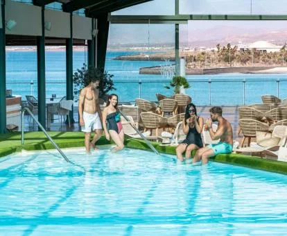 Varias personas disfrutando de la piscina cubierta con espectaculares vistas de este hotel.