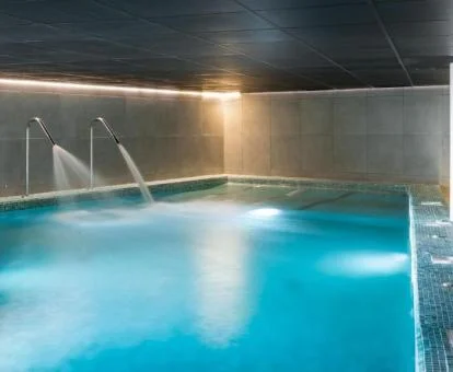 Piscina cubierta con elementos de hidroterapia del spa del hotel.