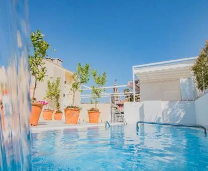 Terraza con mobiliario y piscina exterior con cascada del hotel.