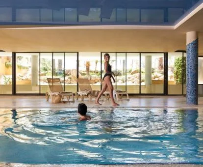 Pareja disfrutando de la piscina con elementos de hidroterapia del hotel.