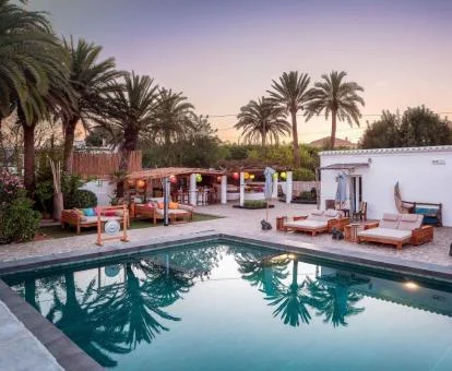 Zona exterior de este hotel con encanto con piscina y palmeras.