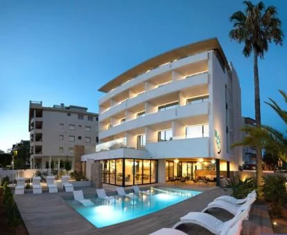 Edificio de este hotel boutique con solarium y piscina con tumbonas en el agua.
