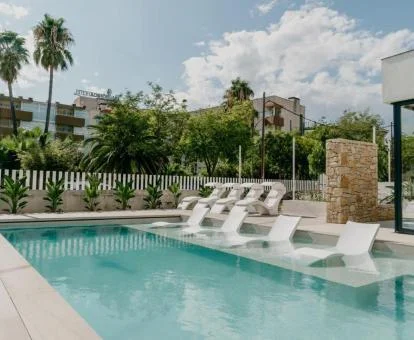 Coqueta zona exterior con piscina con tumbonas en el agua de este hotel romántico.