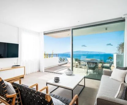 Sala de estar y terraza con mobiliario y fabulosas vistas al mar de una de las suites del hotel.