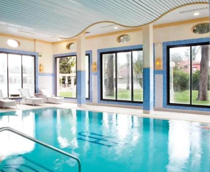 Piscina cubierta con zona de relajación y vistas al exterior del spa.