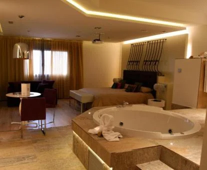 Una de las coquetas habitaciones con bañera de hidromasaje privada cerca de la cama del hotel.
