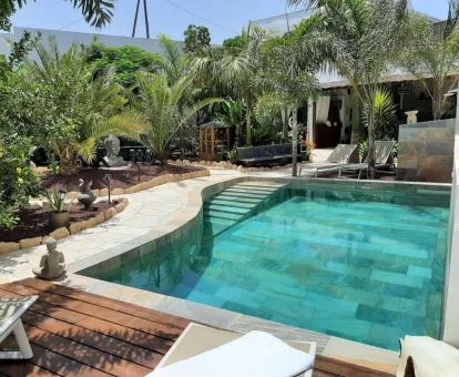 Zona exterior con piscina, mobiliario y bellos jardines del alojamiento.