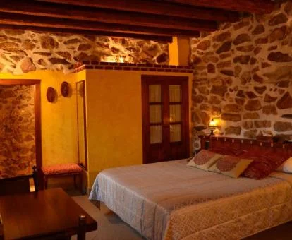 Una Suite Junior del hotel con cama amplia, paredes rústicas de piedra y escritorio.