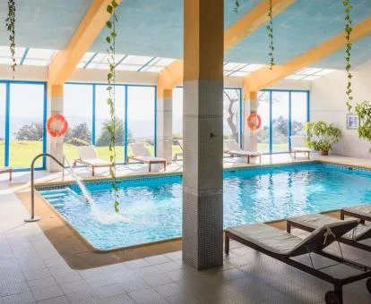 Piscina cubierta del spa con zona de relajación y vistas al exterior.