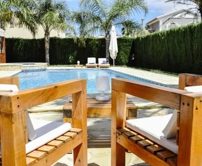 Piscina exterior con mobiliario al aire libre y palmeras de este hotel solo para adultos.