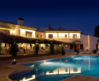 Edificio de este hotel rural con amplia piscina exterior e iluminación nocturna.