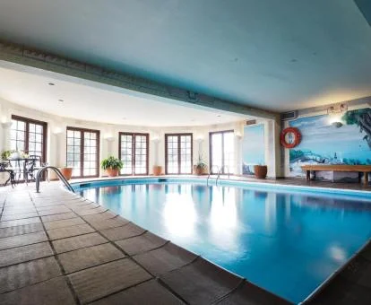 Piscina cubierta con hidroterapia y vistas al exterior del centro de bienestar del hotel.