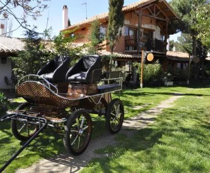 Hermoso hotel rural con zona exterior ajardinada y un carruaje de caballos.