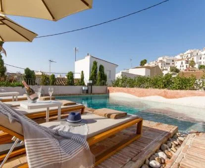 Piscina exterior con solarium, tumbonas y vistas al pueblo de este hotel solo para adultos.