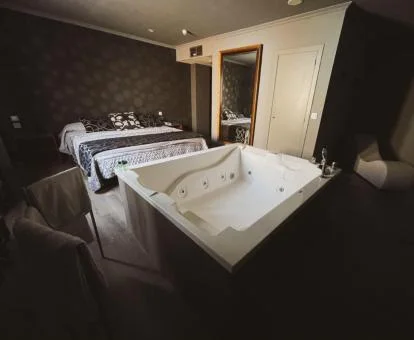 Una de las habitaciones con gran jacuzzi privado cerca de la cama.
