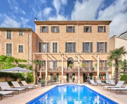 Edificio rural con piscina exterior y solarium con tumbonas.