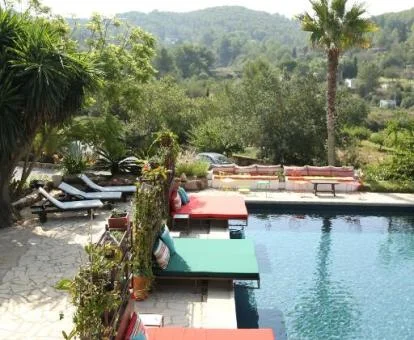 Amplia piscina exterior con camas, tumbonas y rodeada de naturaleza de este hotel solo para adultos.