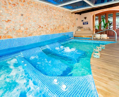 Piscina con elementos de hidroterapia y tumbonas en el agua del spa del hotel.