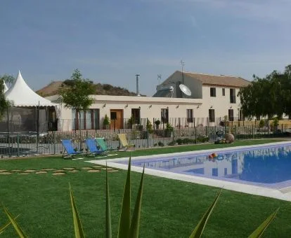 Establecimiento rural con amplios jardines y piscina exterior.