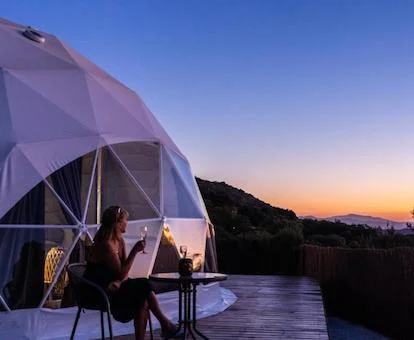 Mujer disfrutando del atardecer en la terraza de esta habitación burbuja con espectaculares vistas.