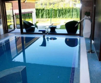 Piscina cubierta con hidroterapia y vistas al exterior del centro de bienestar del hotel.