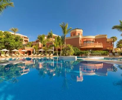 Espectacular hotel solo para adultos con una amplia piscina y solarium con palmeras.