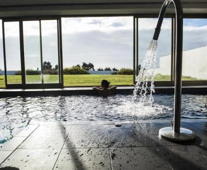Mujer disfrutando de las vistas desde la piscina con elementos de hidroterapia del spa.