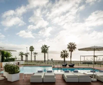 Piscina exterior con tumbonas y acceso directo a la playa del hotel.